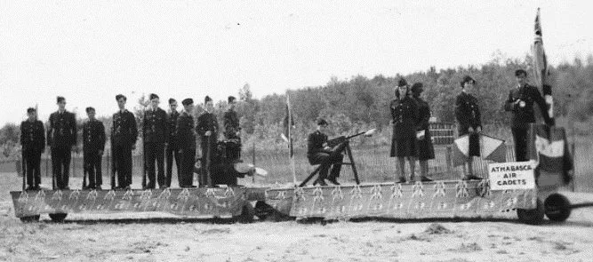 A group of young people in Canadian Air cadets uniforms standing on the back of two flatbed trailers, preparing to march in a parade.